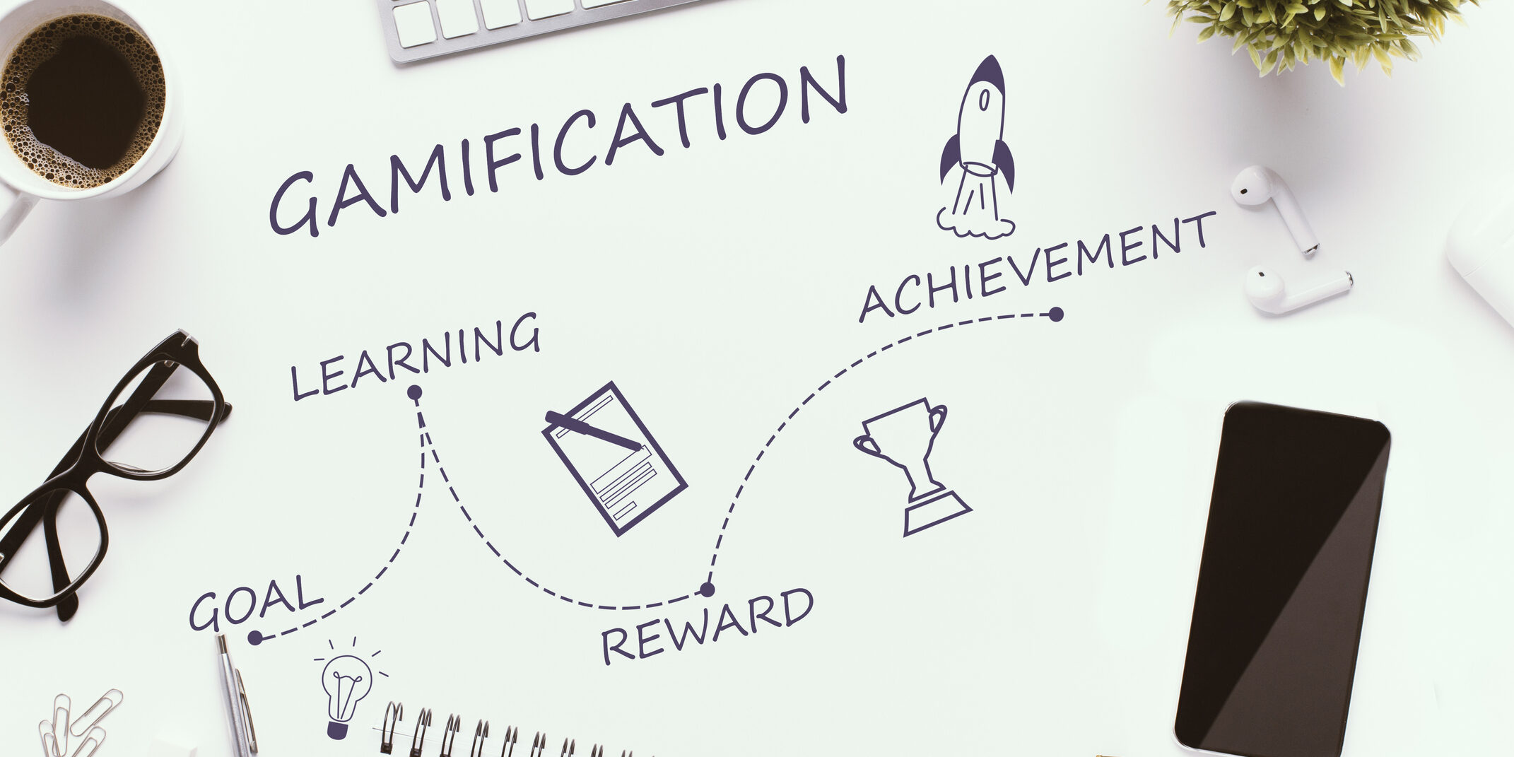 Gamification stages on white workplace - goal, learning, reward and achievement, top view